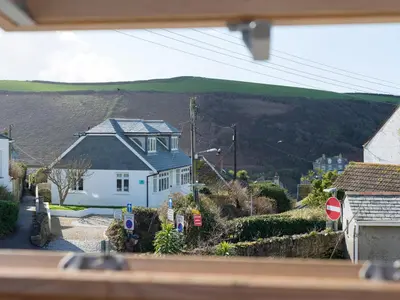 a view of a house with a hill in the background at Sea Glimpses in Port Isaac