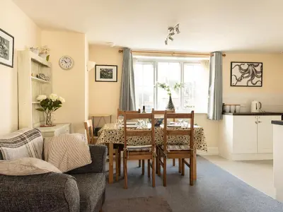 a living room with a dining room table and a kitchen at Sea Glimpses in Port Isaac