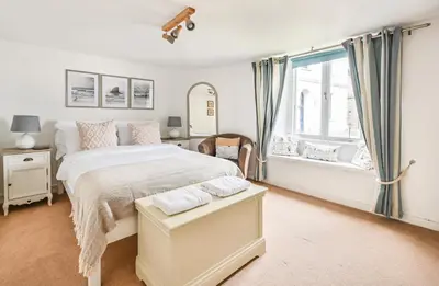 a white bedroom with a large bed and a window at Cosy Bake Cottage, Great Location in Looe, Cornwall in Looe