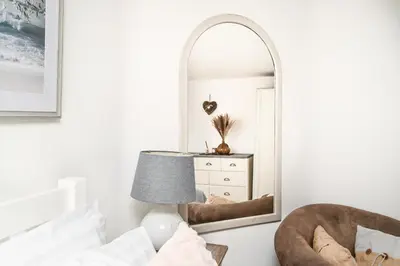 a bedroom with a mirror and a chair at Cosy Bake Cottage, Great Location in Looe, Cornwall in Looe