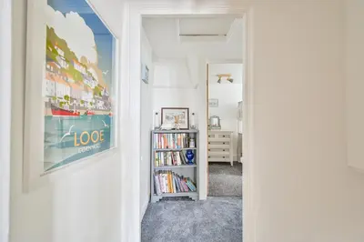 a hallway with a book shelf filled with books at Cosy Bake Cottage, Great Location in Looe, Cornwall in Looe
