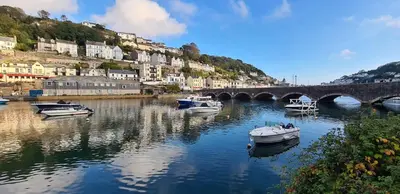 a group of boats in a river with a bridge at Cosy Bake Cottage, Great Location in Looe, Cornwall in Looe