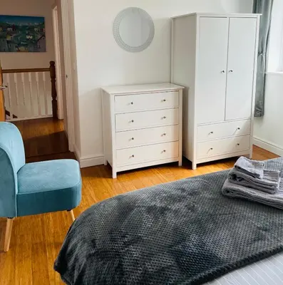 a bedroom with a dresser and a bed and a chair at Sunny Corner, Padstow. Spacious 3 bedrooms, 2.5 bathrooms, parking, garden. in Padstow