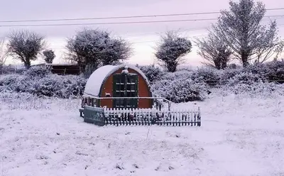 a small house in a field covered in snow at Glamping Pod in St Austell Sleeps 2 with Spa Pool in St Austell