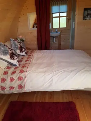 a large white bed in a wooden room at Glamping Pod in St Austell Sleeps 2 with Spa Pool in St Austell