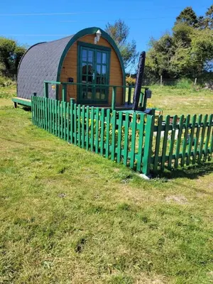 a green fence in front of a small building at Glamping Pod in St Austell Sleeps 2 with Spa Pool in St Austell