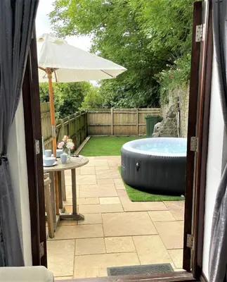 a backyard with a hot tub and an umbrella at The Stables - Detached Cottage with Private Garden & Hot Tub in St Austell