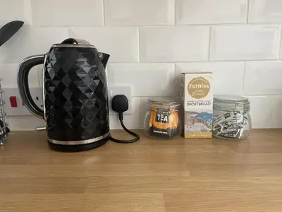 a tea kettle on a counter next to a box of honey at The Stables - Detached Cottage with Private Garden & Hot Tub in St Austell