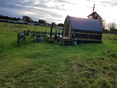 a barn with a table and a bench in a field at Cozy Cabin Retreat in Saint Austell in Lanivet