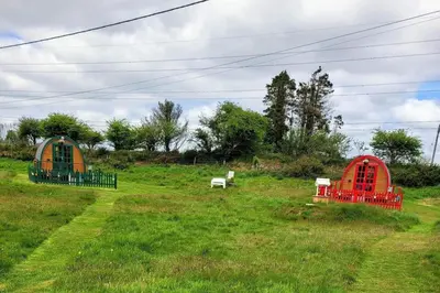 two small shelters in a grassy field at Cozy Cabin Retreat in Saint Austell in Lanivet