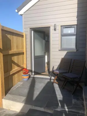 a patio with a door and a chair and a house at Piala retreat in Phillack