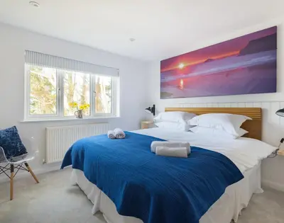 a bedroom with a large bed with a blue blanket at Beaches in Polzeath