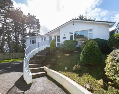 a white house with stairs in front of it at Beaches in Polzeath