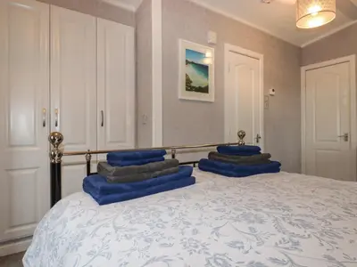 a bedroom with a bed with blue pillows on it at Sycamore Lodge in Helston