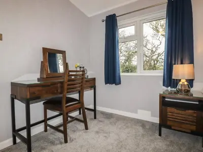 a room with a desk and a mirror and a window at Sycamore Lodge in Helston