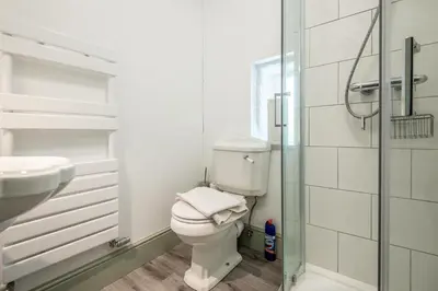 a white bathroom with a toilet and a sink at Doolans in Falmouth