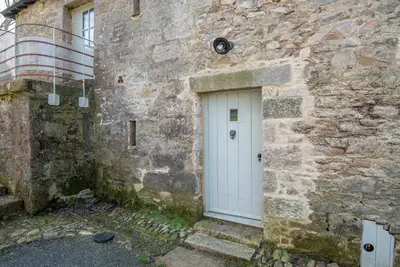 a white door on the side of a stone building at Doolans in Falmouth