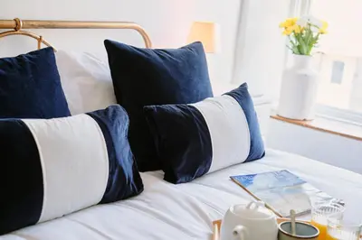 a bed with blue and white pillows and a book on it at Finest Retreats - Scallop Cottage in Porthleven