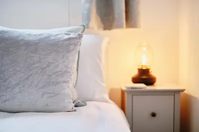 a bed with a pillow and a lamp on a night stand at Finest Retreats - Scallop Cottage in Porthleven