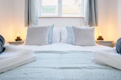 a white bed with white pillows and a window at Finest Retreats - Scallop Cottage in Porthleven