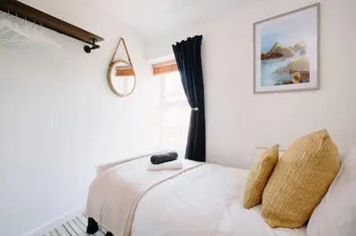 a bedroom with a white bed with a window at Finest Retreats - Scallop Cottage in Porthleven
