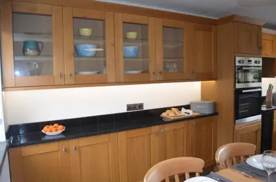 a kitchen with wooden cabinets with bowls of fruit on the counter at The Cottage, Treliggon Farm in Lanivet