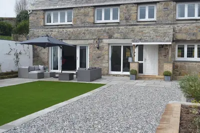 a stone house with an umbrella and a lawn at The Cottage, Treliggon Farm in Lanivet