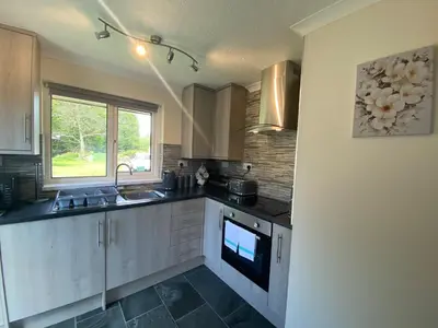 a kitchen with white cabinets and a sink and a window at Lands End in Liskeard