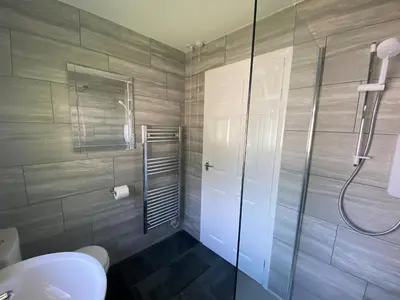a bathroom with a shower and a toilet and a glass door at Lands End in Liskeard