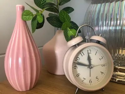 a pink alarm clock sitting on a table with vases at Padstow Lodge - Padstow Holiday Village in Padstow
