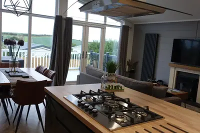 a kitchen and living room with a stove top oven at Padstow Lodge - Padstow Holiday Village in Padstow
