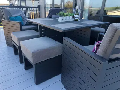 a table and chairs on a deck with a glass of wine at Padstow Lodge - Padstow Holiday Village in Padstow