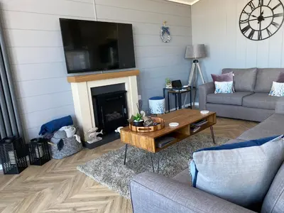 a living room with a couch and a table and a fireplace at Padstow Lodge - Padstow Holiday Village in Padstow