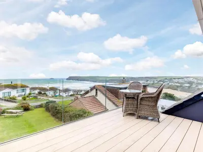 a balcony with two chairs and a table on a deck at Atlantis in Polzeath
