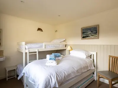 a bedroom with two bunk beds and a chair at Atlantis in Polzeath