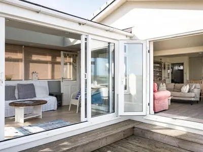 a sliding glass door on a patio with a living room at Atlantis in Polzeath