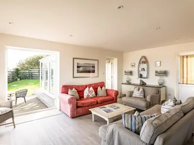 a living room with a red couch and a table at Atlantis in Polzeath
