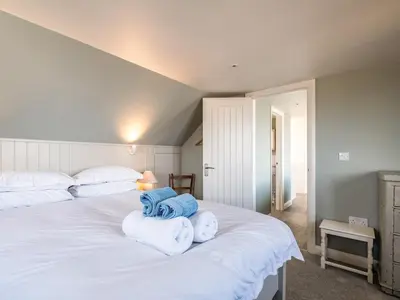 a bedroom with a white bed with towels on it at Atlantis in Polzeath