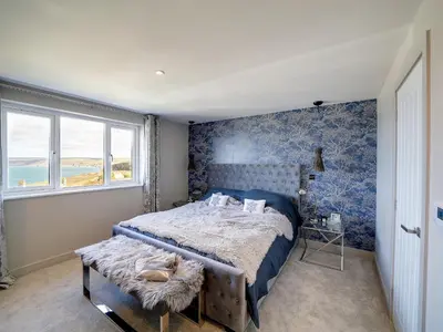 a bedroom with a bed with blue wallpaper at Seahaven in Port Isaac