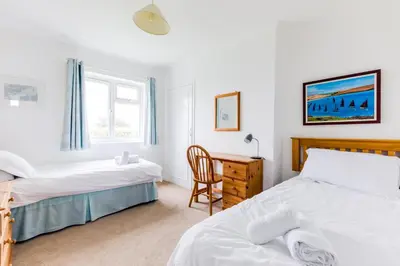 a bedroom with two beds and a desk and a chair at Trebartha in Polzeath
