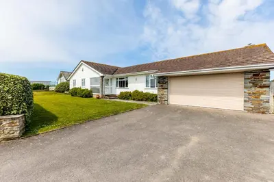 a large white house with a garage at Trebartha in Polzeath