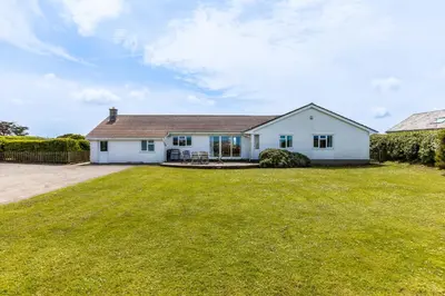 a white house with a large yard at Trebartha in Polzeath