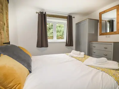 a bedroom with a large white bed with a window at Stall 1- The Stables in Truro