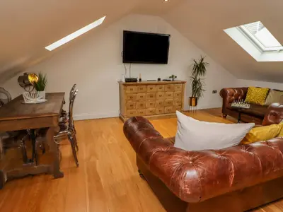 a living room with a leather couch and a television at The Hideaway in St Ives