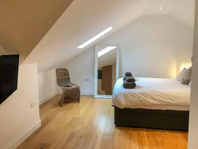 a bedroom with a bed and a mirror and a chair at The Hideaway in St Ives