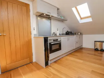a kitchen with white cabinets and a wooden door at The Hideaway in St Ives