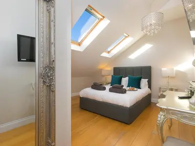 a bedroom with a bed with blue pillows and a mirror at 7 Four Seasons in St Ives