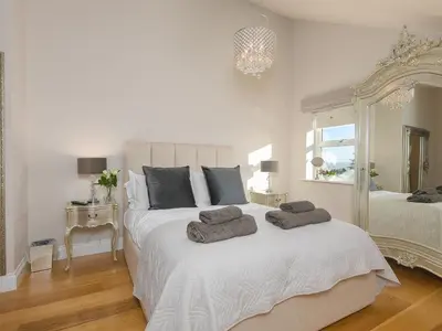 a bedroom with a large white bed with two towels on it at 7 Four Seasons in St Ives