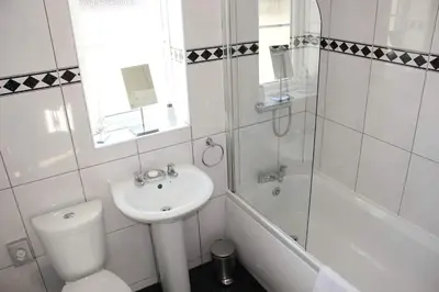 a white bathroom with a sink and a toilet and a tub at Ocean Breeze No 5, Seaview & Parking in Falmouth