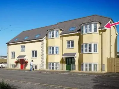a large yellow building with a person standing in front of it at Ocean Breeze No 5, Seaview & Parking in Falmouth